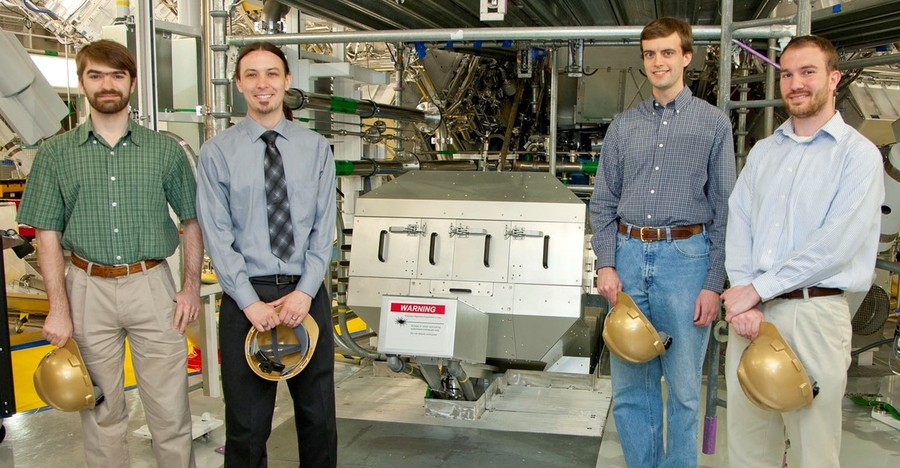 MIT graduate students and alumni (left to right) Hans Rinderknecht (physics), Dan Casey PhD '12 (nuclear science and engineering), Alex Zylstra (physics), and Mike Rosenberg PhD '14 (physics) stand with a neutron spectrometer. Rinderknecht and Zylstra have just been awarded Lawrence Postdoctoral Fellowships.  