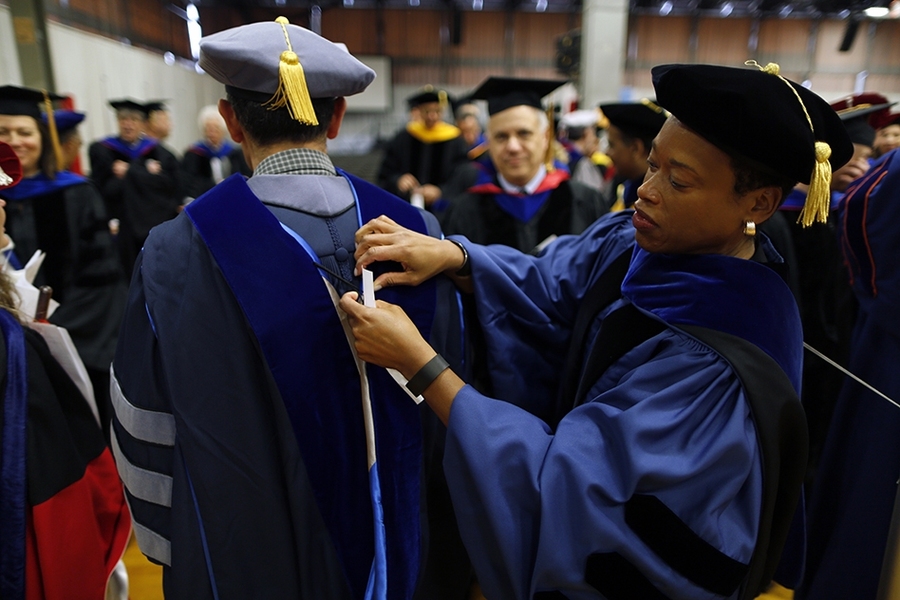 Melissa Nobles, the Arthur and Ruth Sloan Professor of Political Science and head of MIT’s Department of Political Science, helps a colleague with his ceremonial dress. 