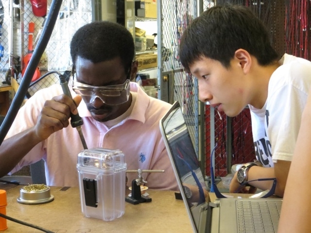 Simon Okaine (left) and Junhyeok of Team Flounder solder one of their electronic systems that will go on their remotely operated vehicle.
