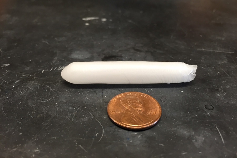 A paraffin wax capsule developed by researchers at MIT is shown next to a penny.