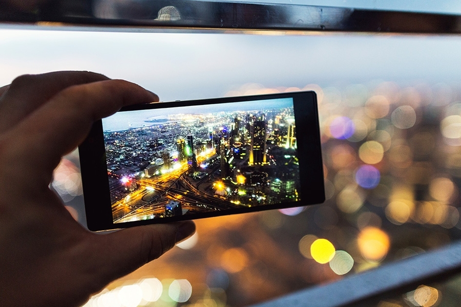 hand holding a smartphone with city lights on the screen