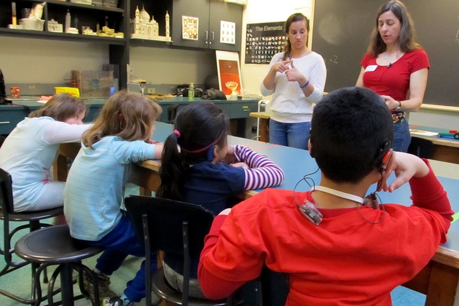 Students receive instructions from Amy Fitzgerald (right), outreach program coordinator at the MIT Edgerton Center, while Isabelle Pisini (left) translates the directions to American Sign Language. 