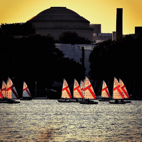 On a summer's day MIT sailboats can be seen backlit by the setting sun.