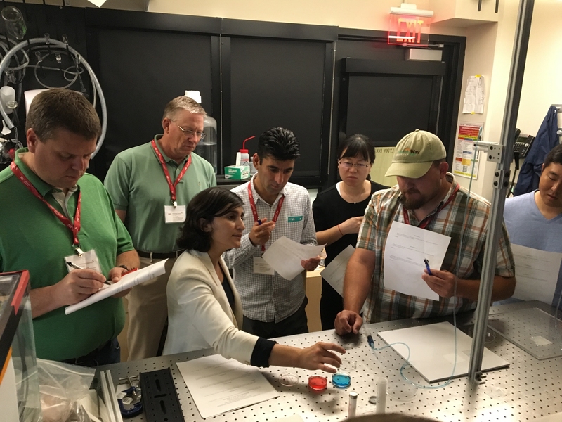 MIT Professor Lydia Bourouiba (seated) leads a lab demonstration and activity for participants to think through the concepts of interfacial dynamics and fluid fragmentation that she presented in her lecture earlier in the course. 
