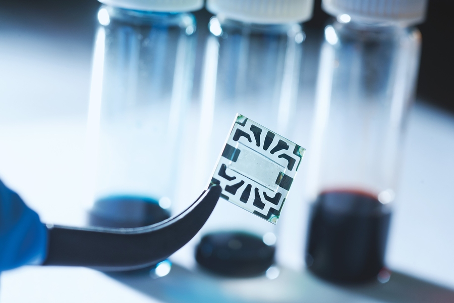 A new flexible graphene solar cell developed at MIT is seen in the transparent region at the center of this sample. Around its edges are metal contacts on which probes can be attached during tests of device performance.