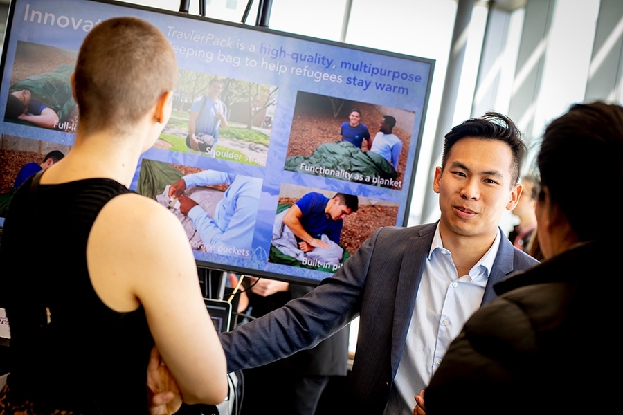 A team member of TravlerPack, which won a $10,000 prize, explains to attendees the team's water-resistant sleeping bag for refugees that withstands extremely cold temperatures, comes equipped with mosquito nets, and can be zipped together with other bags to fit entire families.