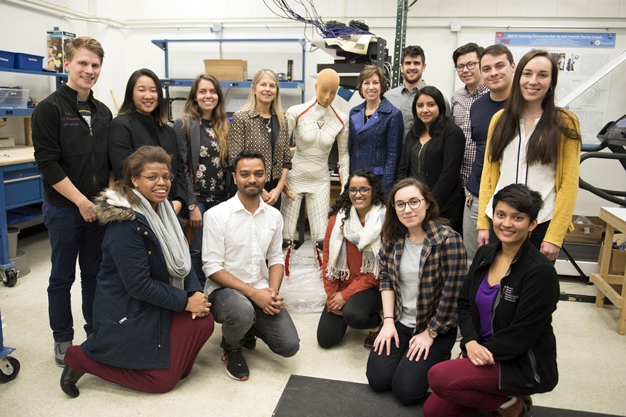 NASA Johnson Space Center director Ellen Ochoa (blue jacket) visited with MIT Professor Dava Newman (standing, fourth from left), students, and guests during a visit to the Department of Aeronautics and Astronautics' Man Vehicle Lab, with which Newman is associated. The mannequin in the center is wearing a BioSuit future spacesuit concept that Newman developed.