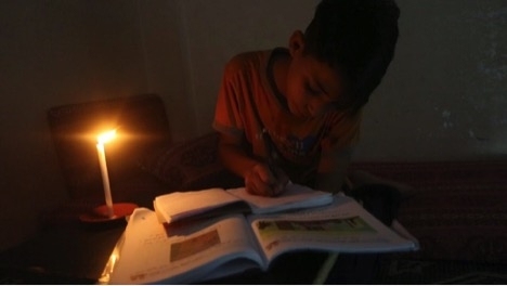 Gazan pupil doing homework by candlelight prior to solar kit installation