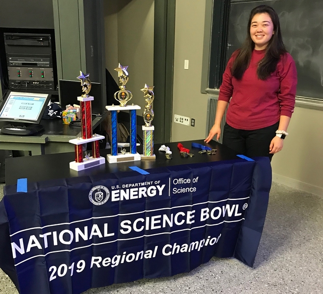 Founder and coordinator Kathleen Schwind, an MIT student in the Department of Urban Studies and Planning, poses by the trophies for this year's Northeast Regional Middle School Science Bowl.