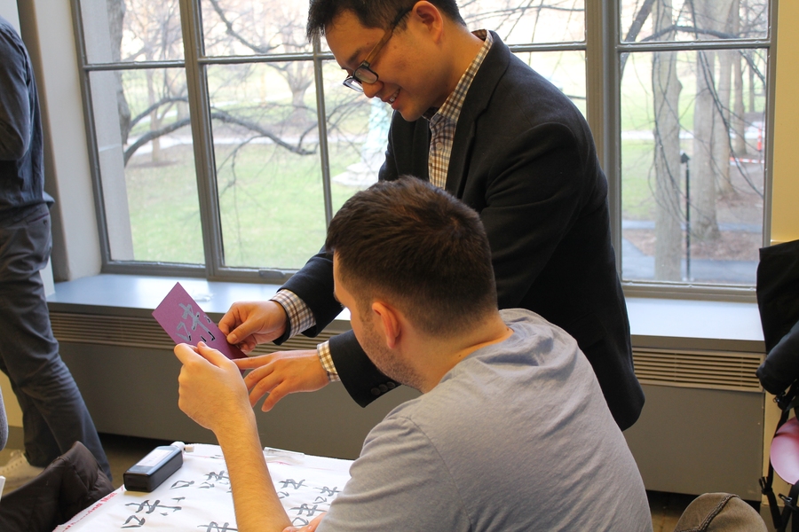 Kang Zhou (standing) reviews a student's work. “When we appreciate calligraphy works in class, we also analyze the life experiences and stories of the calligraphers to further our understanding,” he says.