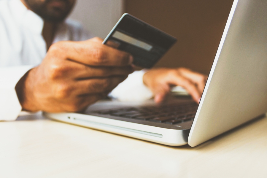 Blurry stock photo of a person holding a credit card and using a laptop