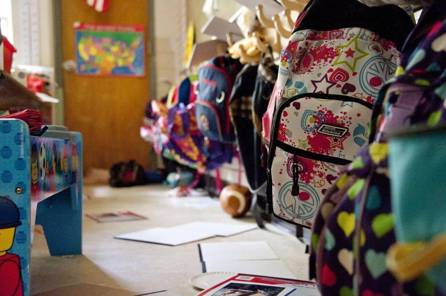 A blurry photo of children's backpacks in a school hallway