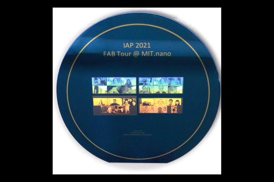 Photo of a circular navy blue silicon wafer etched with 29 faces reflecting colors of light, a bit like a rainbow hologram, with blues at the top and reds at the bottom