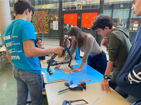 Photo of several students standing around a table with robot parts