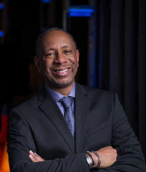 Portrait photo of Ceasar McDowell smiling and wearing a suit
