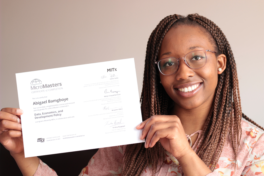 Photo of a woman smiling at the camera, holding MITx MicroMasters completion certificate.