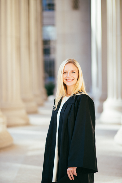 Photo of Grace Moore in a graduation gown on the MIT steps with columns in the background