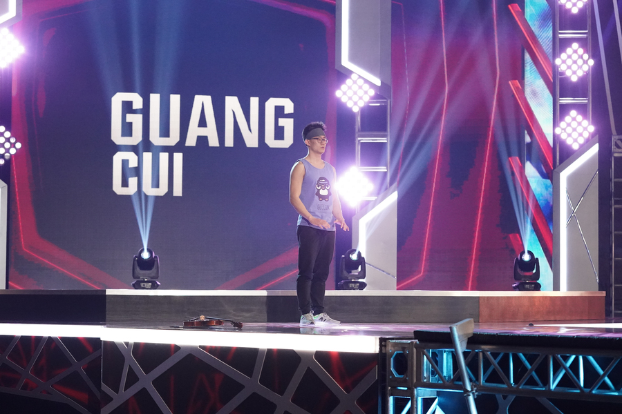 TV screen grab of Guang Cui standing on the precipice of an obstacle course. His posture is tense and his face is focused.