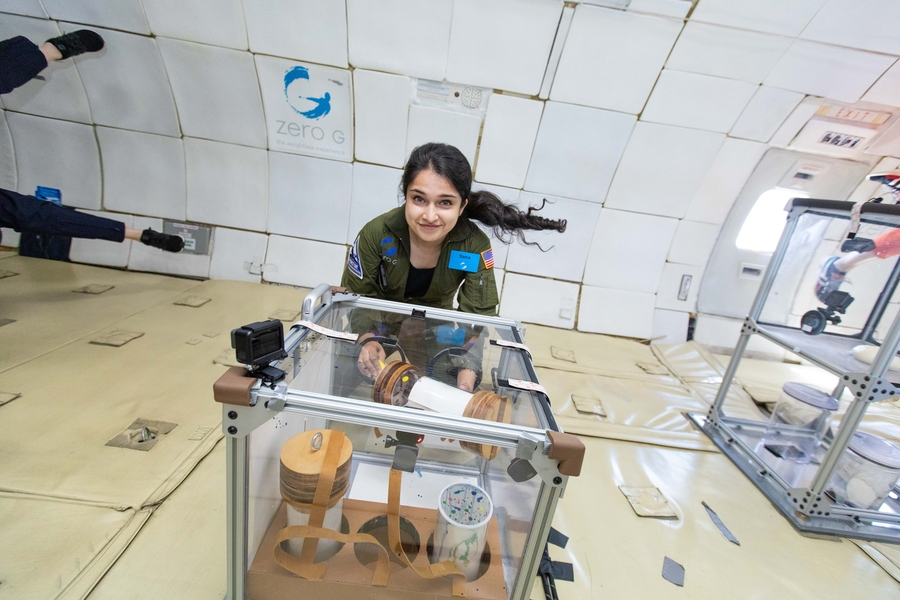 Photo of a woman demonstrating equipment in a microgravity environment