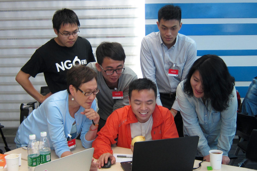 Chinese NGO leaders, an MIT graduate student, and Jing Wang gathered around a laptop