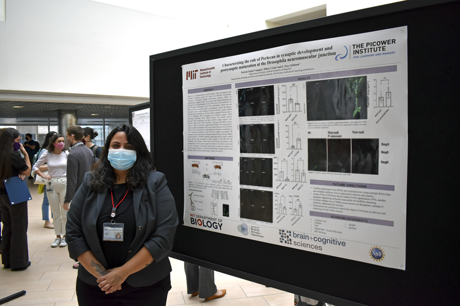 Photo of Patricia Pujols, masked, standing next to her research poster