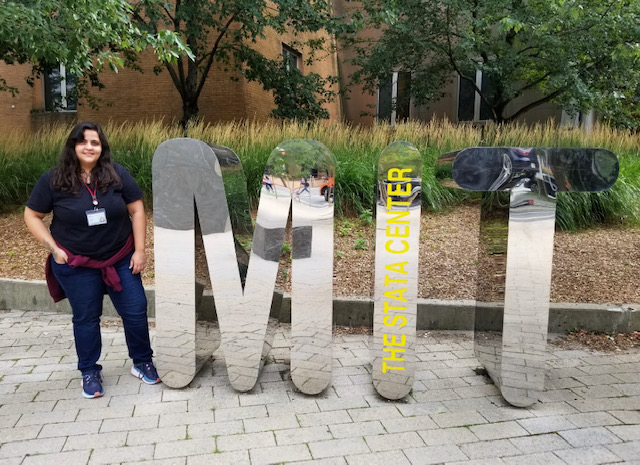 Photo of Patricia Pujols standing next to a sculpture of the letters "MIT"