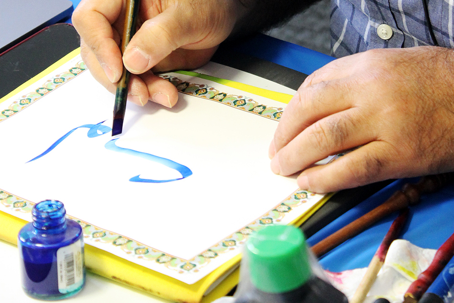 Closeup of hand holding pen to make a calligraphic figure.