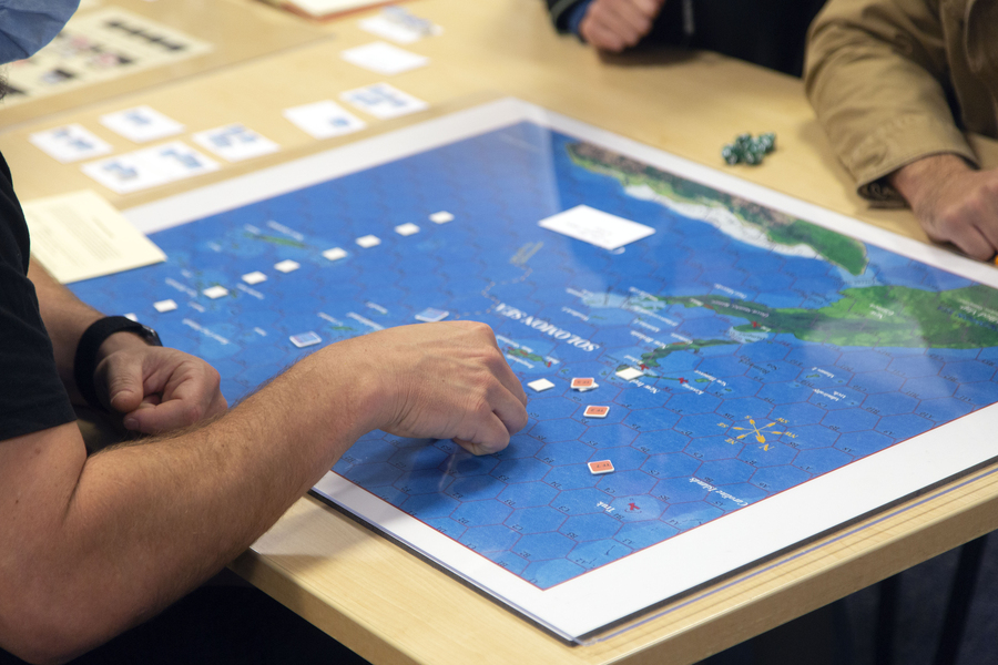 Photo of hands manipulating counters on a hex-based war-game board
