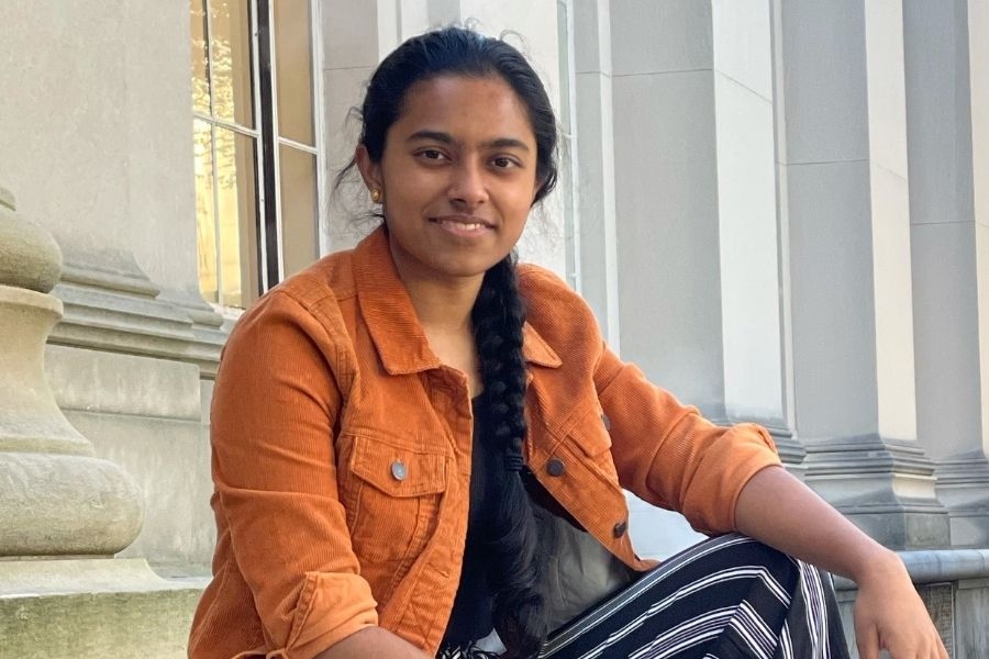 Photo of a young woman sitting on steps smiling.