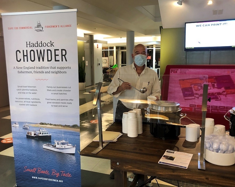 Man standing behind a table serving cups of chowder