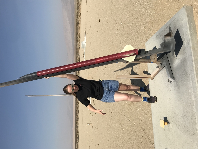 Photo of Summer Hoss mounting rocket taller than herself out in a testing field