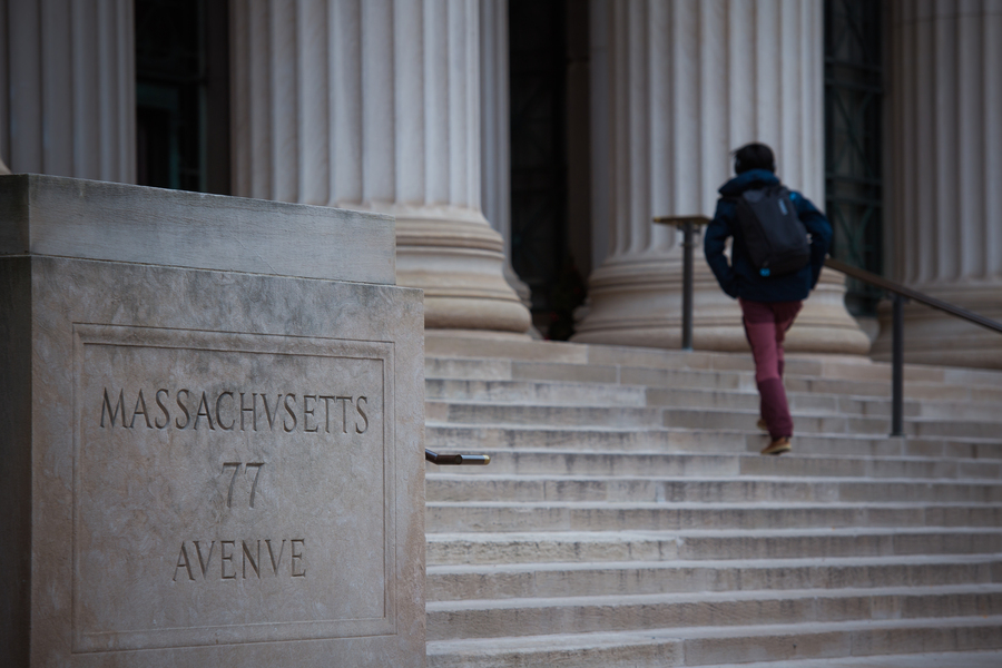 A person photographed from behind walks up the steps to 77 Massachusetts Avenue, MIT’s main entrance 