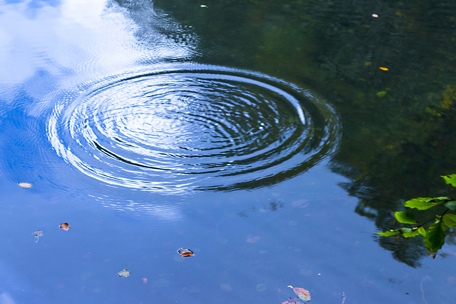 Photo of circular ripples in a blue pond 