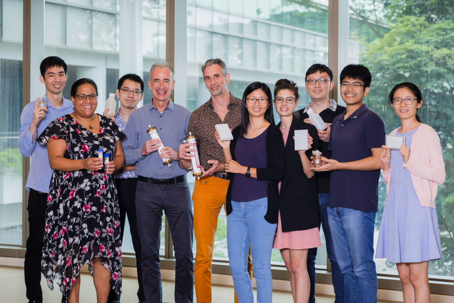 Ten people pose for a photo, each of them holding up an item used for wastewater surveillance