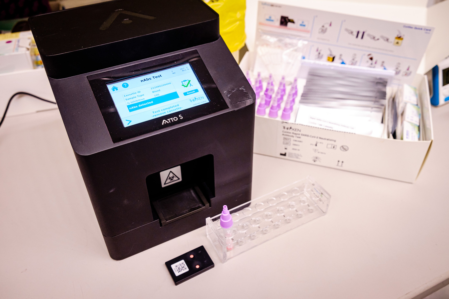 Photo of antibody test kids in soft focus background and an electronic reader in the foreground