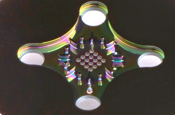 A zoomed-in photo of the cooling technology - a small piece of metal with tiny holes drilled in the middle of it where fluid spurts out of.