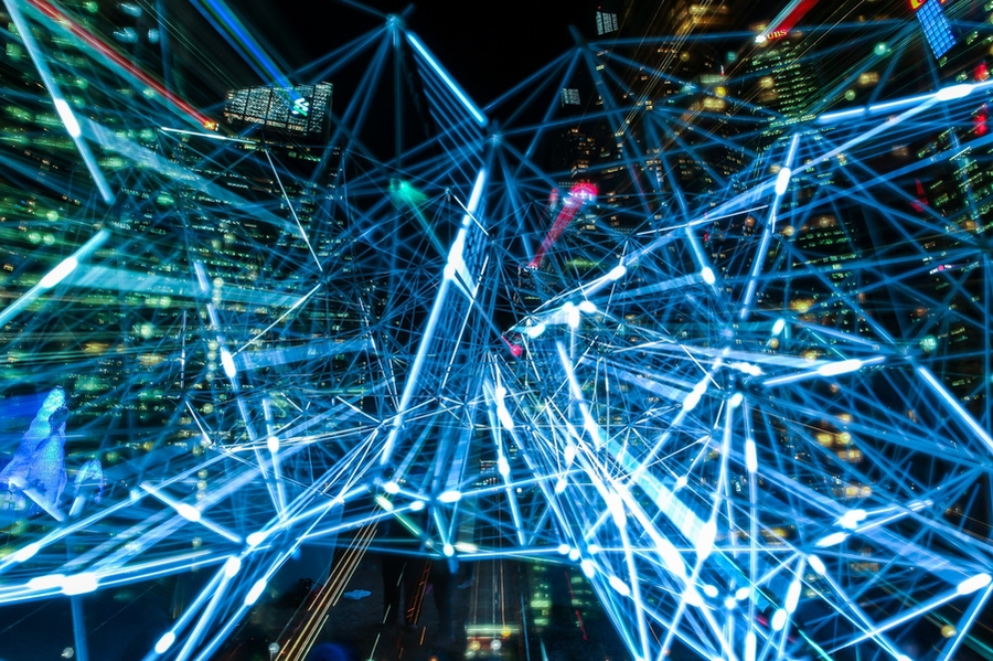 Abstract image of a lattice of glowing blue lines overlaid on a nighttime cityscape