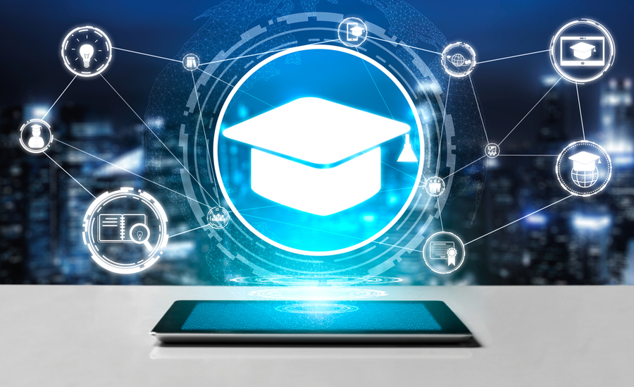 Abstract image of a phone laying flat on a table, with a hologram of a graduation cap with icons representing education connected by lines hovering over it. 