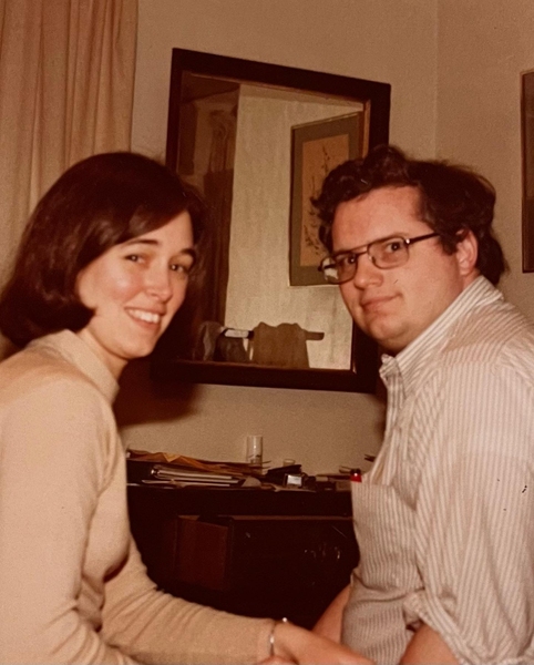 Faded candid photo of young Tom Eagar and his wife Pam sitting in a room, turning to look at the camera