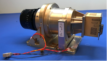The Agile MicroSat’s Camera payload before integration. It's a metal cylinder with electronics at one end and a lens at the other.