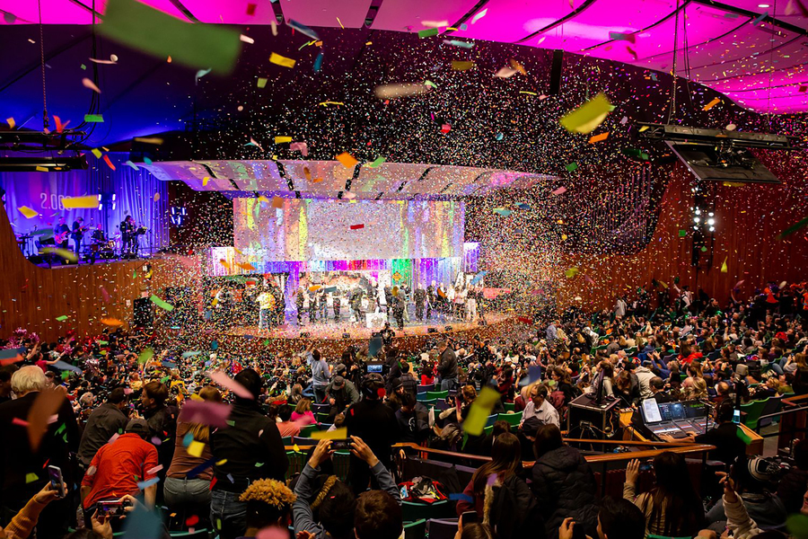Photo of Kresge Auditorium showing confetti in the air, students on stage, and a full house audience cheering on the celebration.