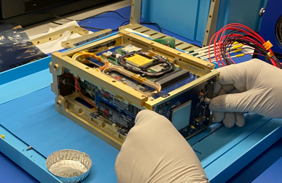 A gold rectangular box, roughly the size of a tissue box, is opened by nitrile-gloved hands to reveal its components.