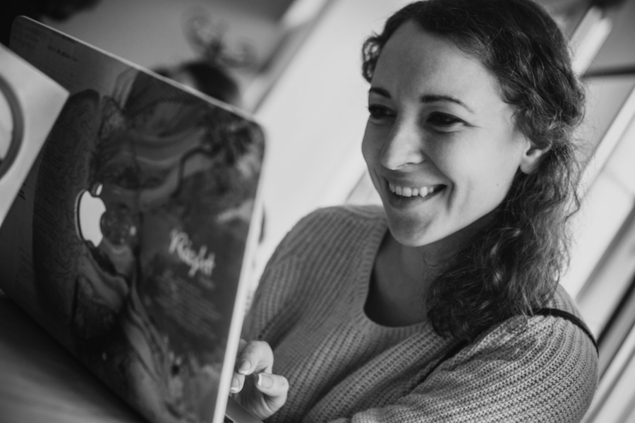 Black and white photo of Tetiana Herasymova smiling at an open laptop.