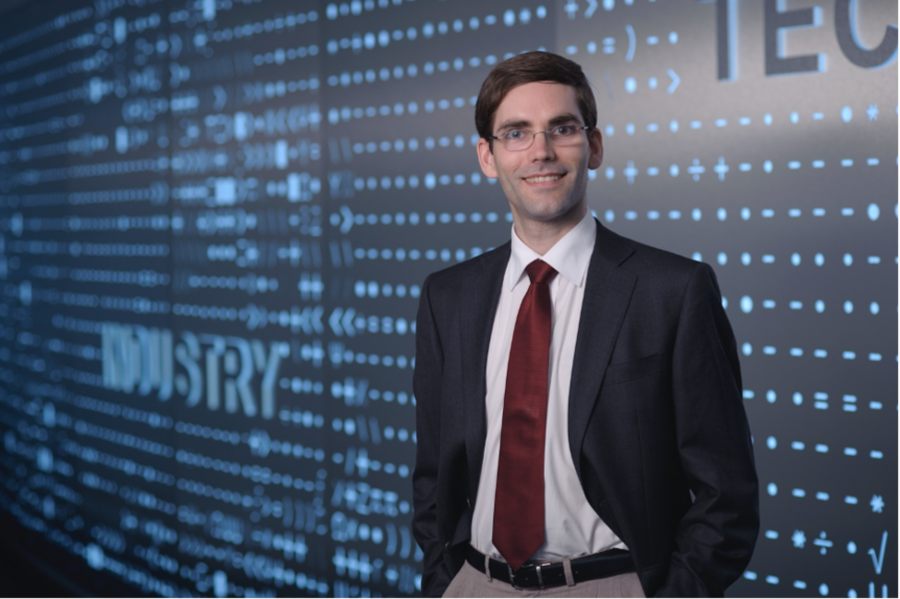 Tomás Palacios stands in front of a large blue screen which reads "Industry”.