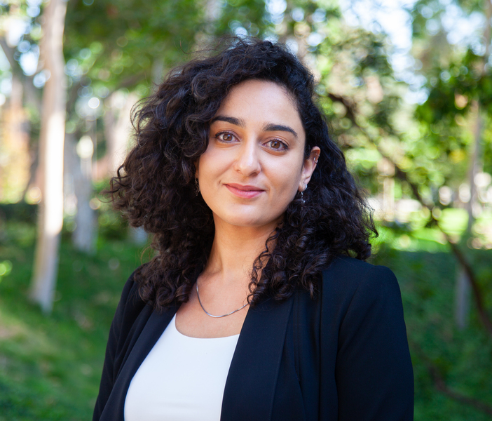 Headshot photo of Zidani with a black blazer and a backdrop of trees
