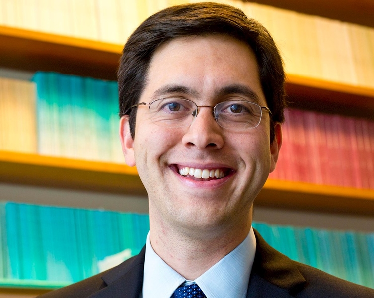 Headshot of Matthew Notowidigdo standing in front of a bookshelf