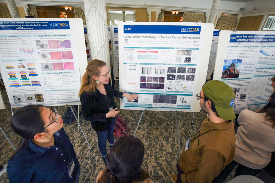 At a poster session, Caroline McCue explains her research to a handful of listeners.