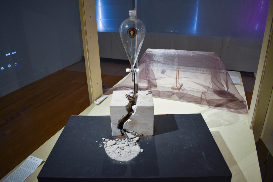 A glass flask on a metal pole set in a broken block of concrete