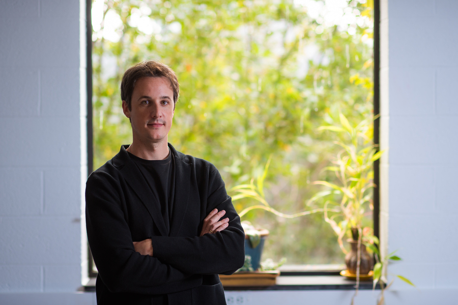 Cesar Terrer standing in front of a window with a green tree in the background