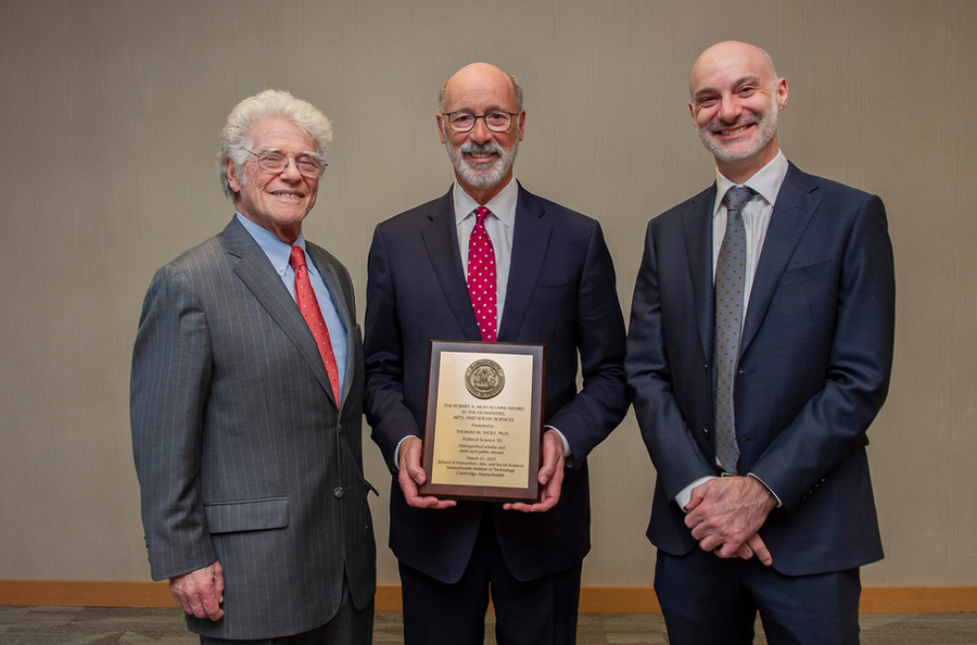 The three men wear suits and pose for a photograph. Wolf holds his award plaque that has the MIT seal on top and small text below.